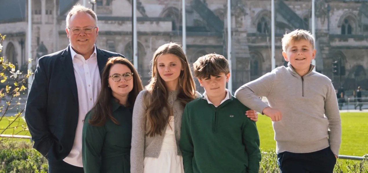 Family standing together outside in the sun.