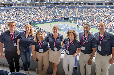 Group photo inside large tennis stadium in front of tennis court