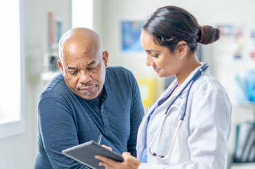 Doctor speaking to patient in exam room setting.