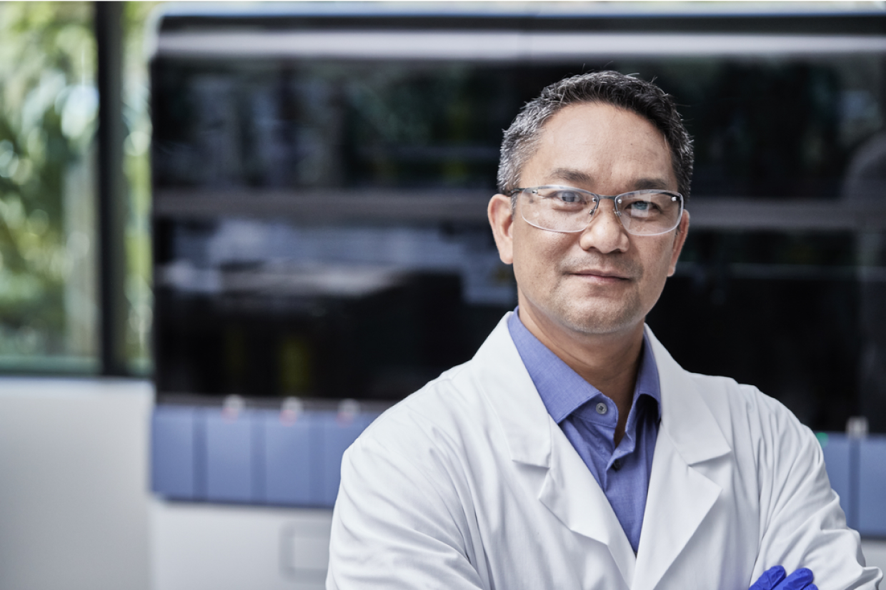 Asian male health provider in lab coat in a lab setting.