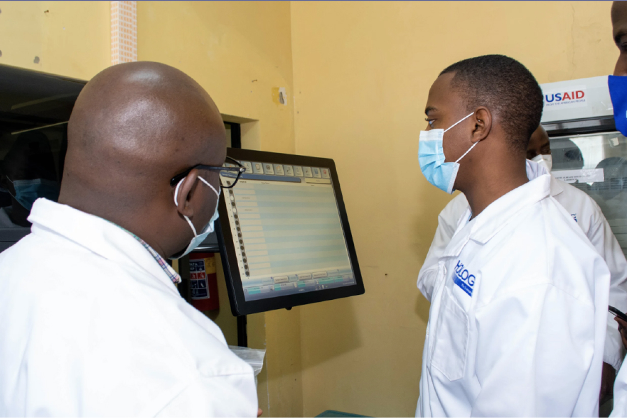 Two African-American male lab technicians looking at a display monitor in a lab setting.