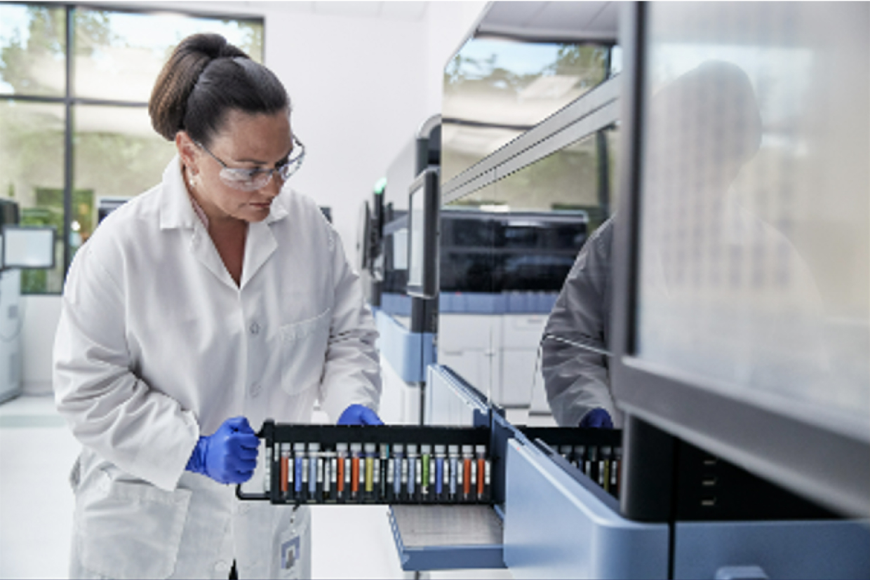 Female lab technician removing rack of vials from Panther system in lab setting.