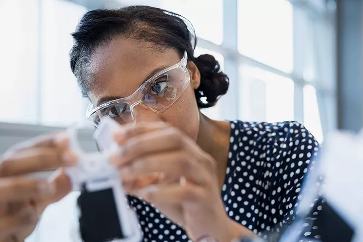 Woman of color inspecting a machine part