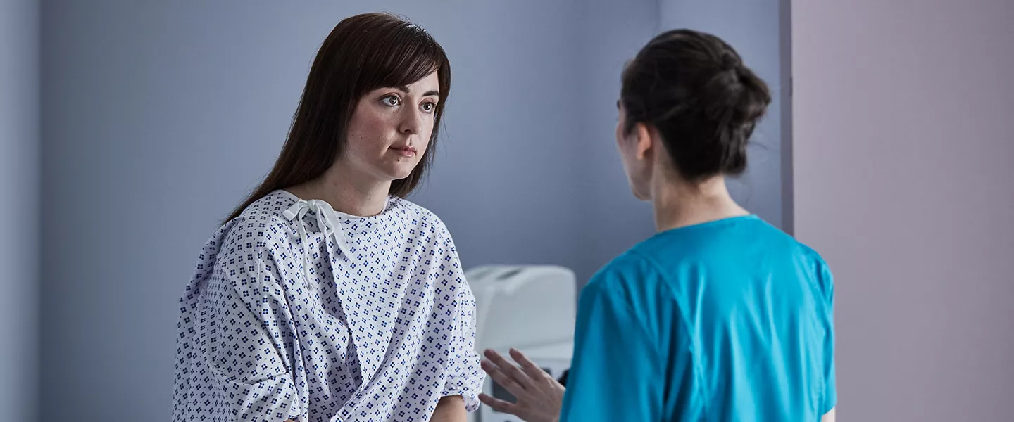 Patient sitting on exam room table speaking with physician.