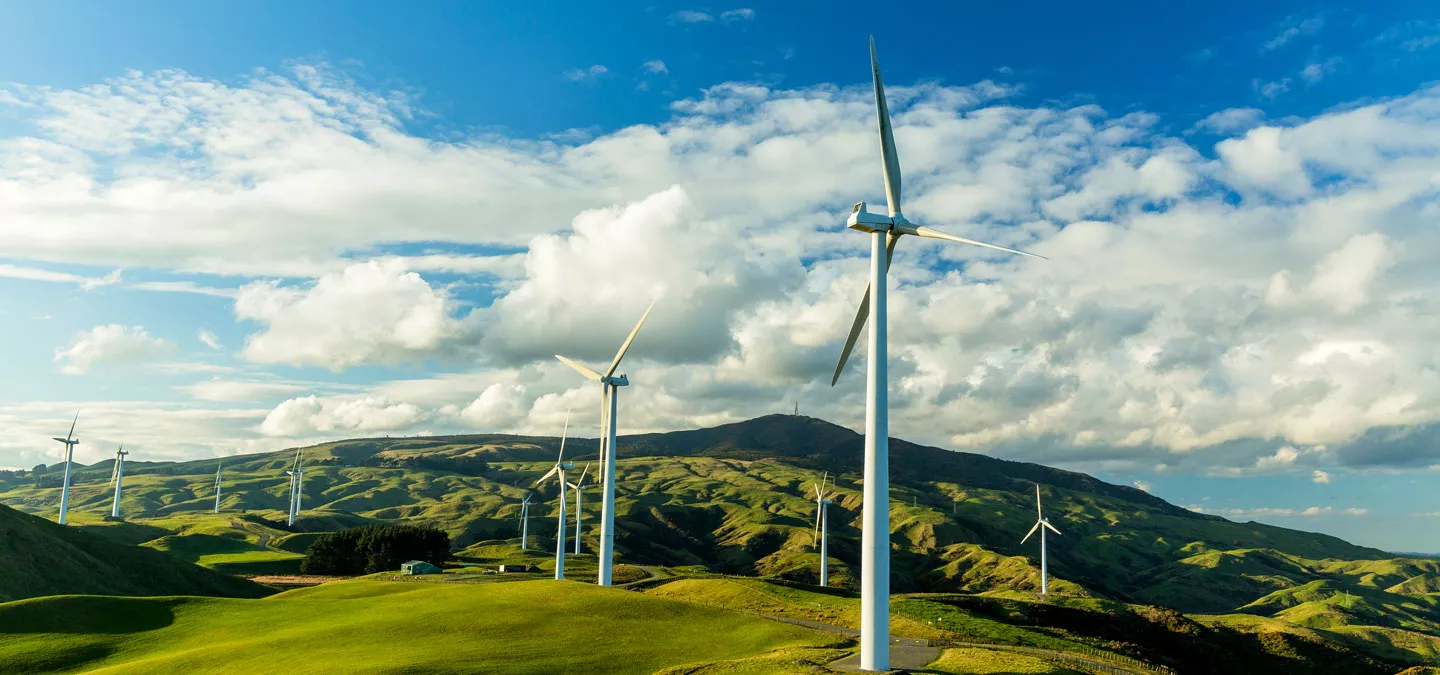 Outside photo of windmills across the landscape during a cloudy day.