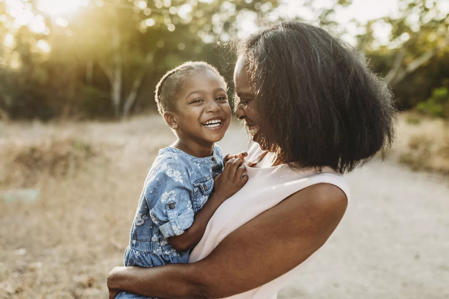 Woman holding child and laughing outdoors