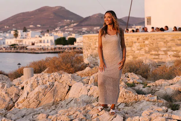 Woman standing on rocks next to water.